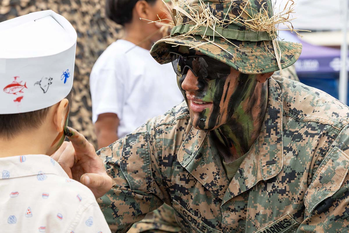A Marine puts face paint on a child