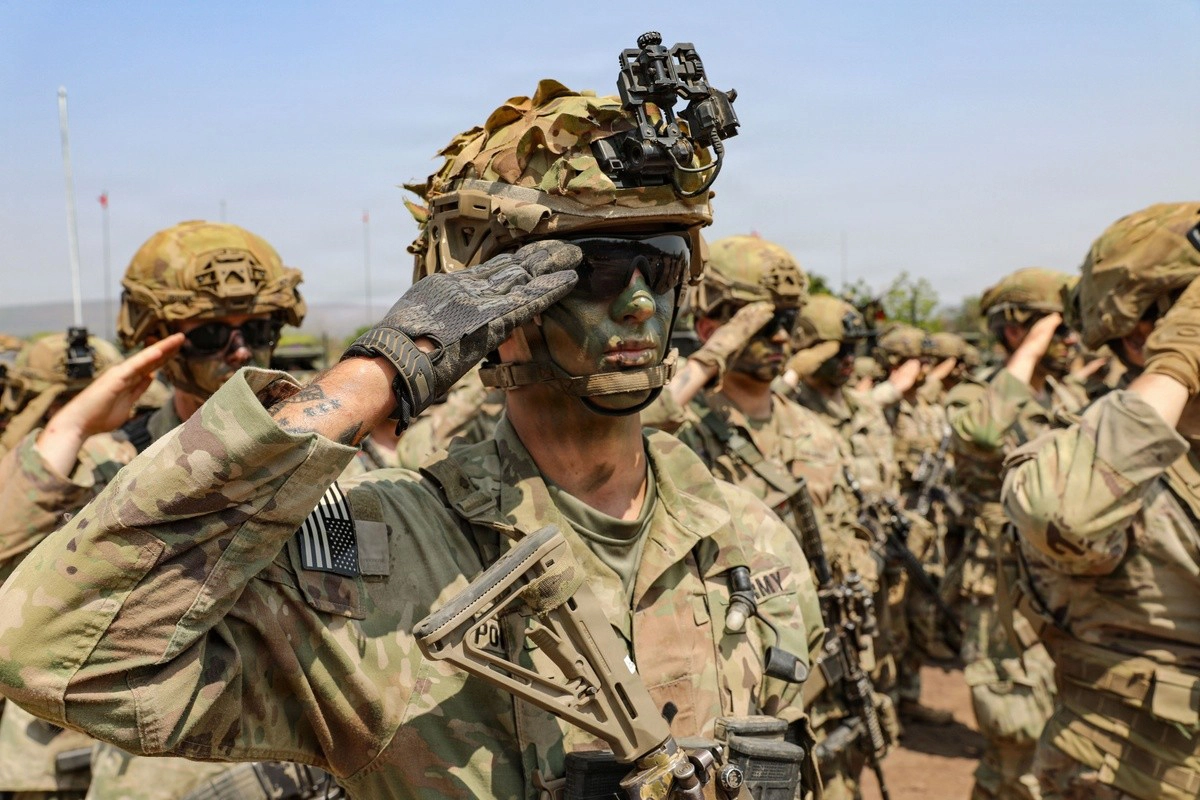 Soldier in kit and camo face paint saluting.