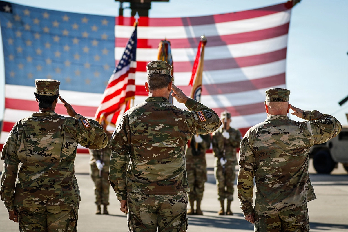 three soldiers saluting a large American flag