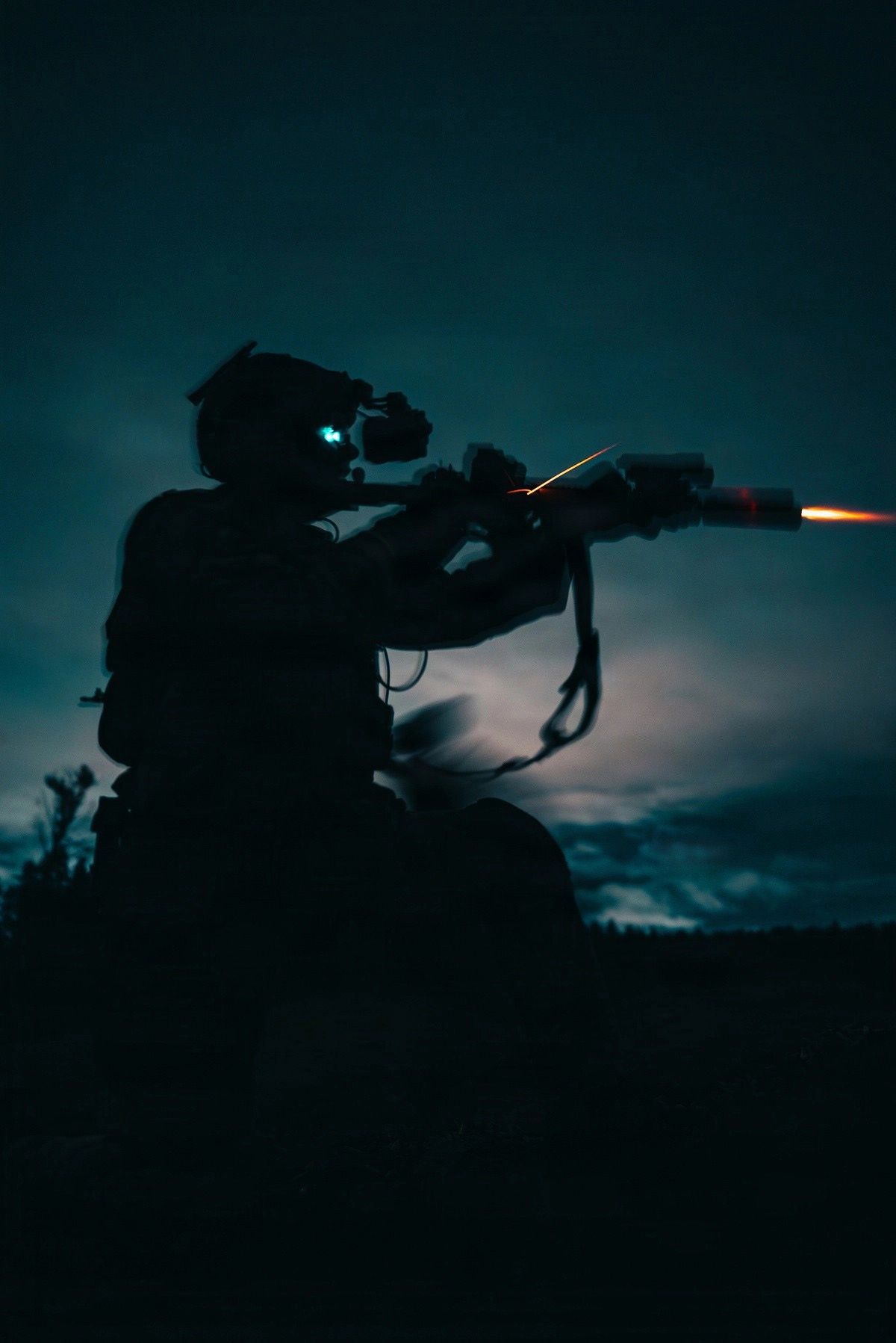 a soldier firing a carbine in low light with NODs